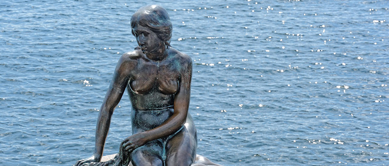 Cropped view of the bronze Little Mermaid statue beside the water.