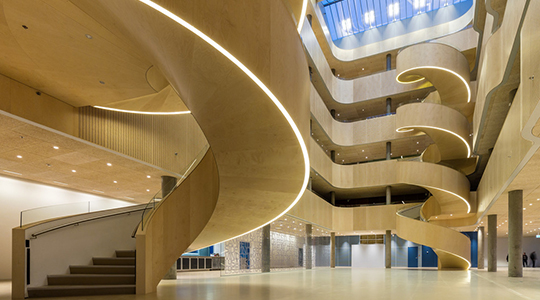 Modern atrium interior with curved wooden balconies and spiral staircases at Psykiatrisygehus i Slagelse.