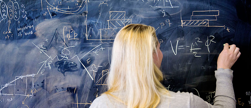Kvinde skriver matematiske formler på en tavle