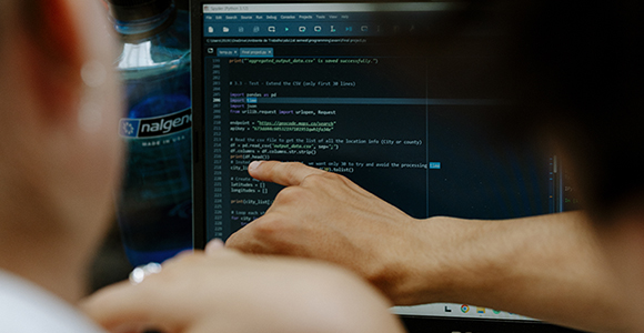 Person pointing at programming code on a laptop screen next to a bottle labeled "nalgene".