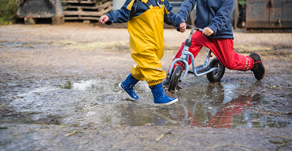 Børn der leger i vandpytter