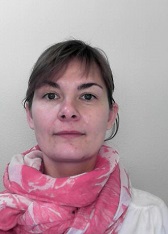 Kvindeportræt med pink mønstret tørklæde foran en lys væg.