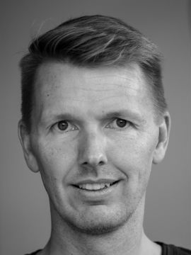 Sort-hvidt portræt af mand Sort-hvidt hovedportræt af en mand med kort hår, der ser mod kameraet.