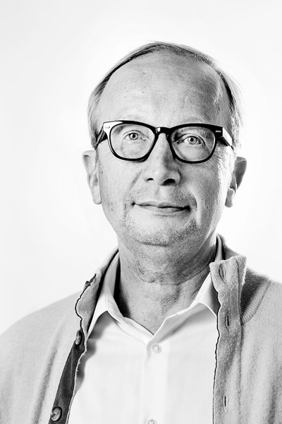Thorbjoern Knudsen portrait Black-and-white portrait of Thorbjoern Knudsen wearing glasses, a collared shirt, and a light cardigan.