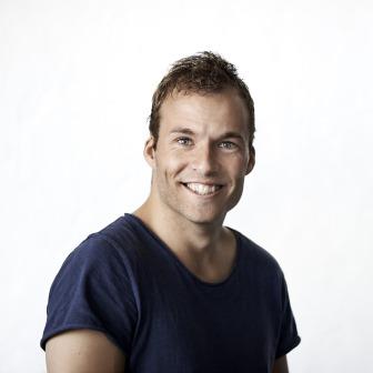 Smiling man in a navy blue shirt posing against a plain light background.