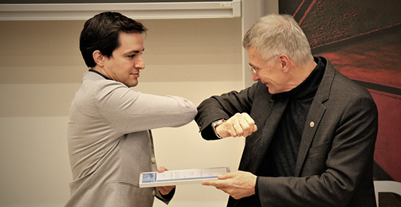 Head of the Mads Clausen Institute, Horst-Günter Rubahn, gives BHJ Young Scientist Award to Jaume Castan Pinos with 'Corona handshake'.