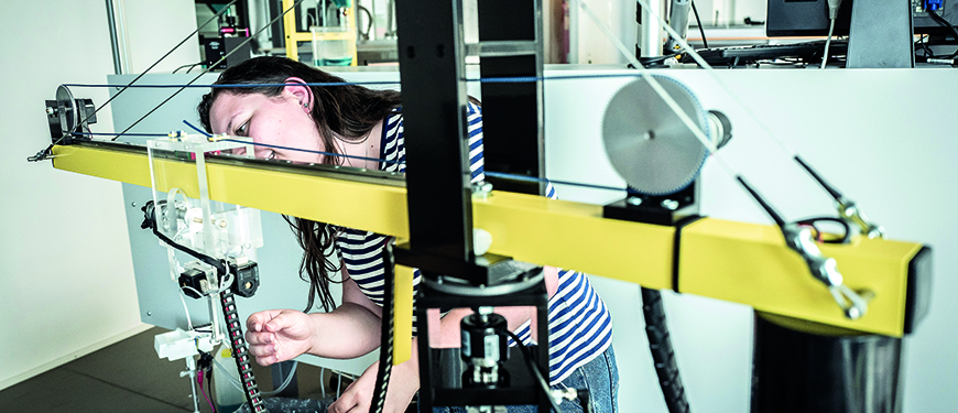 Kvindelig studerende i færd med at undersøge mekanikken på en kran.