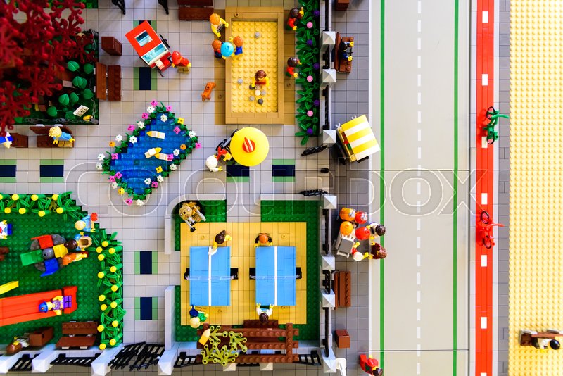 Overblik ovenfra af Leg med Lego-figurer med minifigurer, borde, dam, vej og cykelstier.