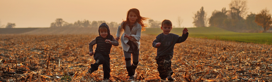 Three children running on a field.