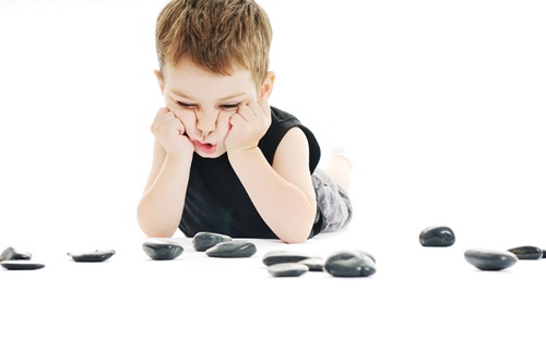 Boy laying on his stomach looking at rocks.