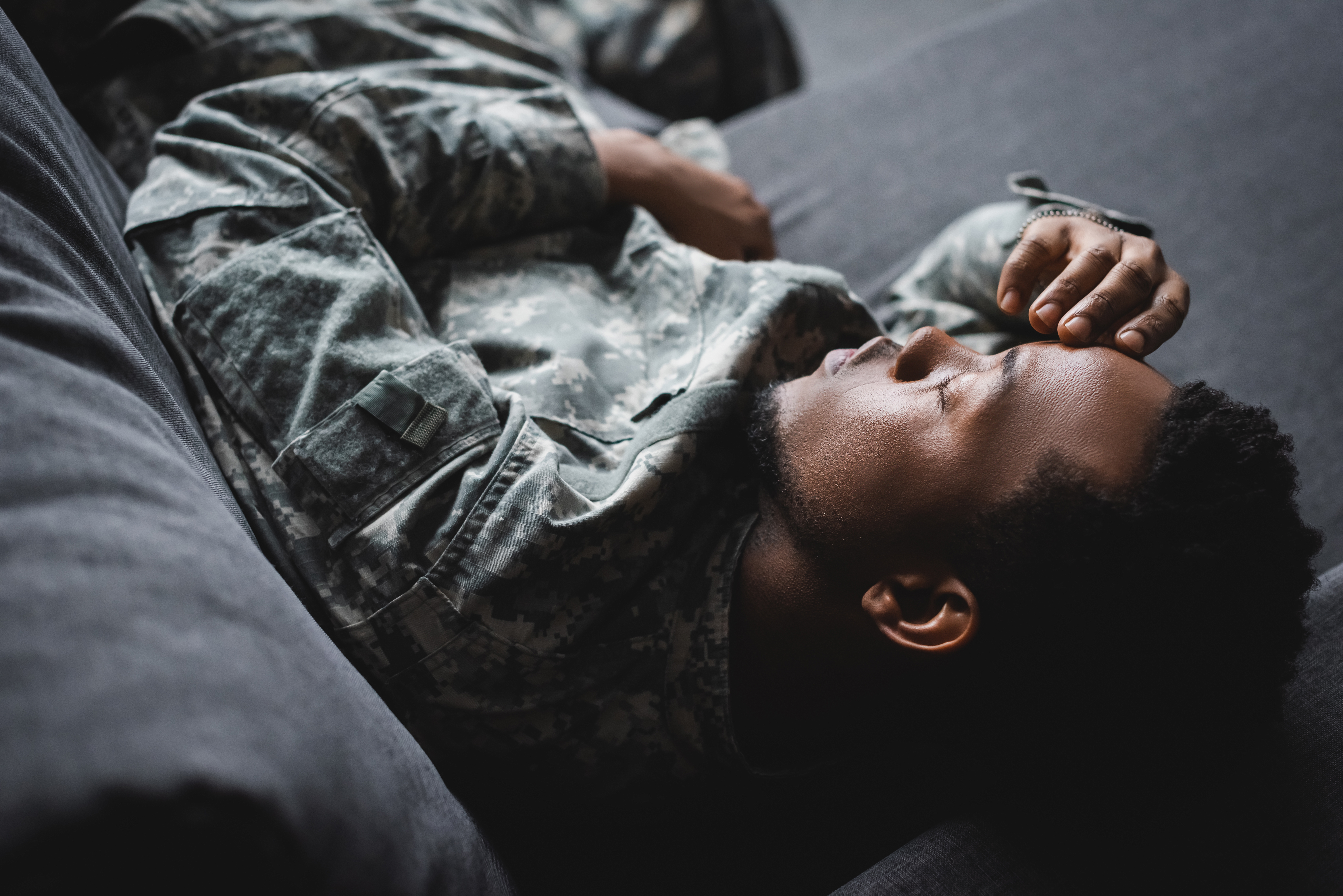 Tired african american soldier in military uniform sleeping in sofa at home