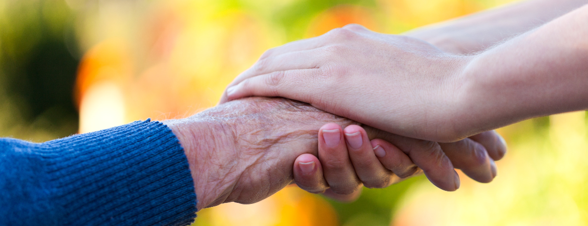 En person holder om en anden persons hånd med begge hænder.