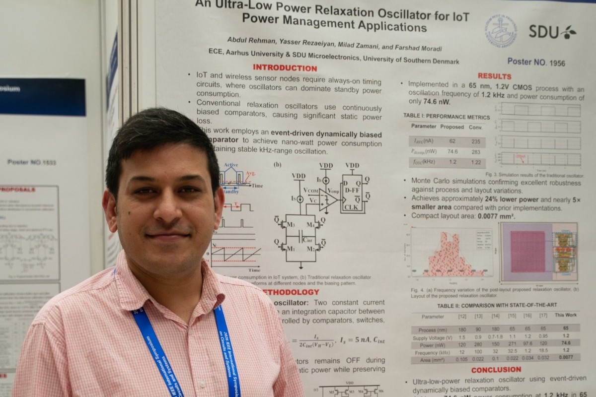 Mand står foran en forskningsposter med titlen "An Ultra-Low Power Relaxation Oscillator for IoT Power Management Applications" på en konference eller udstilling.