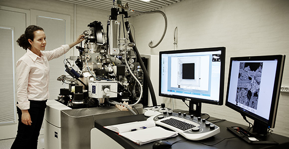 Female researcher standing at the Orion NanoFab microscope