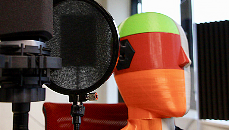 Close-up af professionel studiomikrofon med 3D printed, farvet høre-dummy bagved