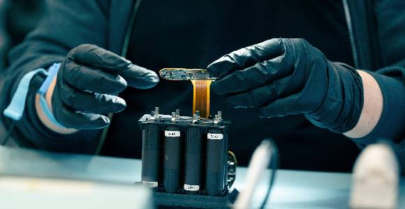 Hands with plasticgloves holding an artifact from GomSpace