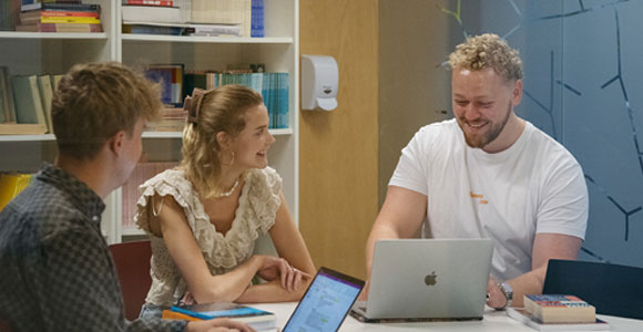 Studerende der sidder om et bord og snakker