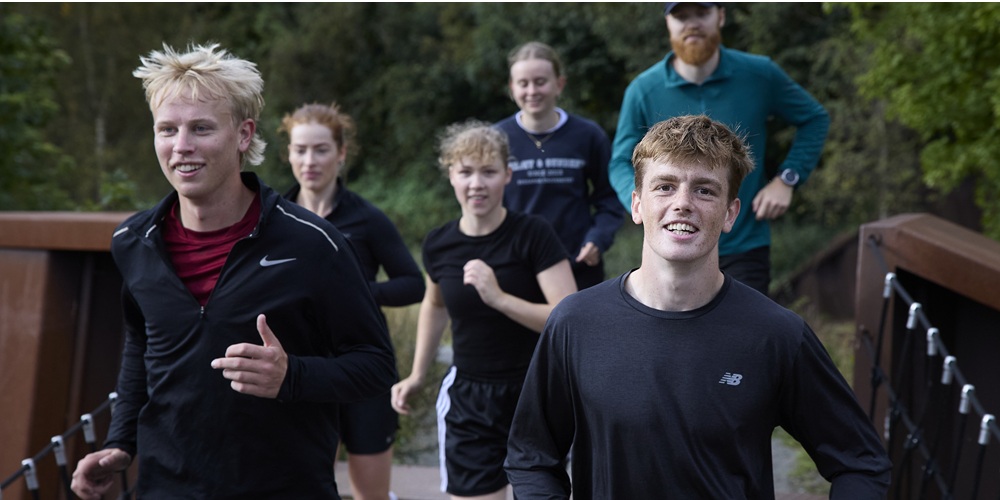 Unge kvinder og mænd i sportstøj, der løber udenfor