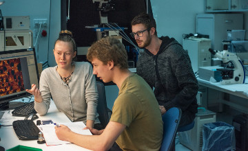 Tre studerende i fysiklaboratorium