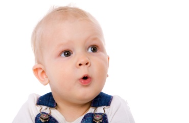 Baby med overrasket ansigtsudtryk og åben mund på lys baggrund.