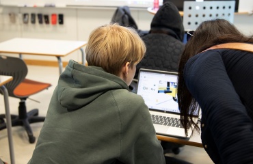 Lærer hjælper elev med lektier i klasseværelse