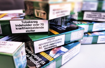 Stablede cigaretpakker med danske advarselsmærkater, herunder "Tobaksrøg indeholder over 70 kræftfremkaldende stoffer".