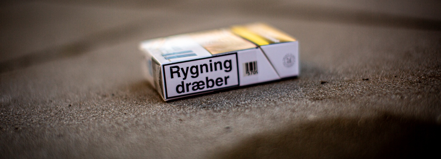 Cigaretpakke på et betontrin med advarselsteksten "Rygning dræber".